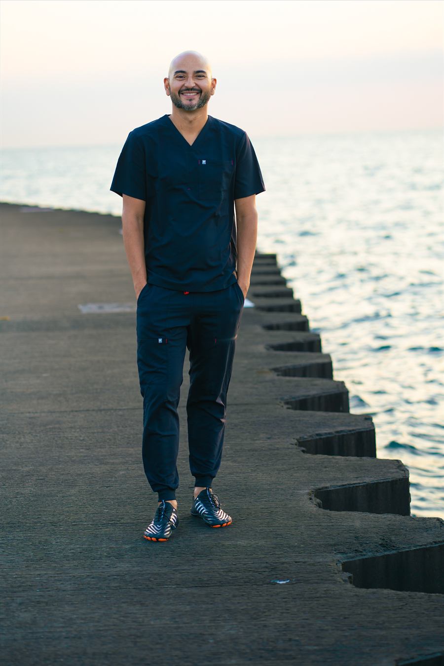 Rios standing along the Chicago lakefront in scrubs, ready for an in-studio or mobile massage appointment